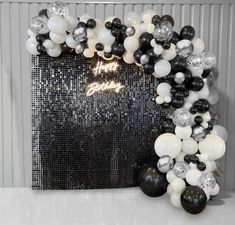 a black and white balloon arch with balloons on the front, along with silver sequins