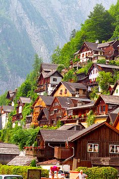 many houses on the side of a hill with mountains in the background