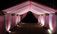 an outdoor wedding venue decorated with pink and white draping, candles and flowers