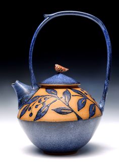 a blue and yellow tea pot with a bird on top