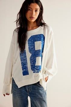 a young woman is standing in front of a white wall wearing a sweatshirt with the number nine printed on it