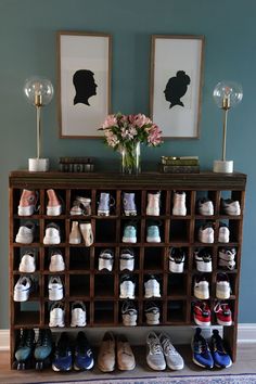 a wooden shoe rack filled with shoes next to two framed pictures on the wall above it