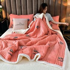 a woman laying in bed under a pink blanket