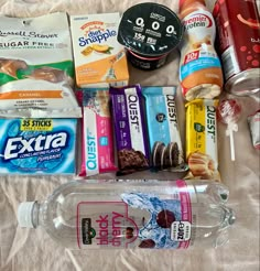 an assortment of snacks and drinks laid out on a bed with the contents in them