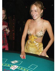 a woman standing in front of a green table with cards on it and smiling at the camera