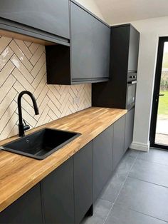 a kitchen with black cabinets and wooden counter tops