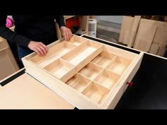 a woman standing over a wooden box filled with drawers