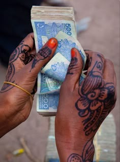 a person with tattoos on their hands holding money