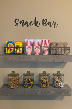 three shelves with snacks and candy in them on top of the wall next to a sign that says snack bar