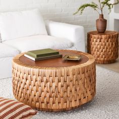 a wicker coffee table sitting on top of a rug next to a white couch