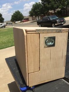 a wooden box sitting on the back of a black dolly in front of a parking lot