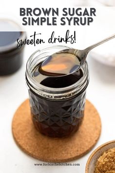 a spoon full of honey sitting on top of a coaster next to some sauce in a jar