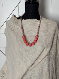 This unique statement necklace is made from unique, round, ceramic, coral colored beads.  For added comfort, this necklace is finished off with a repurposed sari silk and embroidery floss band.  Comfortable and versatile, it goes well with all sorts of outfits. Handmade Coral Spiritual Necklaces, Sari Silk Necklace, Hand-strung Red Coral Beaded Necklace For Gifts, Multi-strand Red Coral Beaded Necklace For Gift, Unique Statement Necklace, Silk Necklace, Artisan Hand-strung Red Coral Necklace, Multi-strand Red Coral Necklace With Polished Beads, Sari Silk