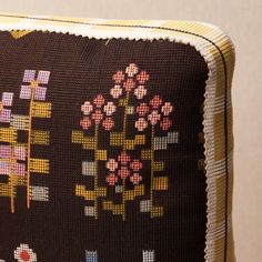 a decorative pillow with flowers and squares on it's back side, sitting on a wooden table