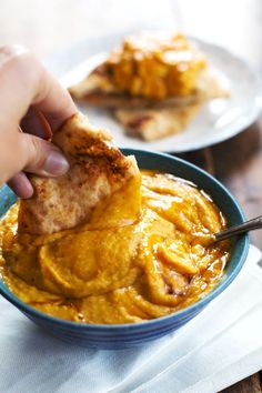 a person dipping some food into a bowl