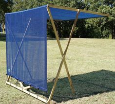 a blue tarp sitting on top of a field next to a wooden structure in the grass