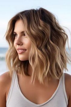 Mid-length beachy waves with highlights to add texture to fine hair. Take a small section of hair on a medium-sized barrel curling iron to achieve such casual curls. Click here to check out more trending medium-length wavy hairstyles this year. Wavy Lob With Highlights, Textured Waves Short Hair, Mermaid Waves Shoulder Length Hair, Mid Length Hair Thick Wavy, Short Beach Waves Hair, Tousled Medium Length Hair, Layered Short Haircuts For Fine Hair, Beachy Haircut Mid Length, Beach Wave Shoulder Length Hair