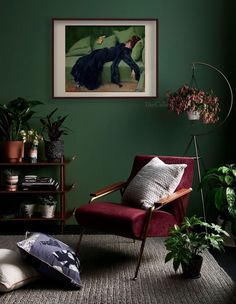 a living room with green walls and plants in the corner, including a red chair