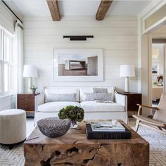 a living room with white furniture and wood beams