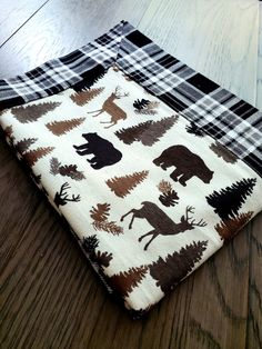 a blanket with moose and trees on it sitting on a wooden floor in front of a wood floor