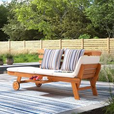 a wooden bench sitting on top of a blue and white striped rug next to trees