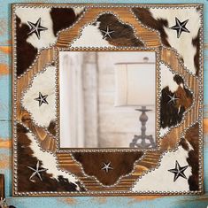 a cowhide mirror with stars on it in front of a blue wall and lamp