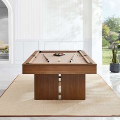 a pool table in the middle of a room with a potted plant on it