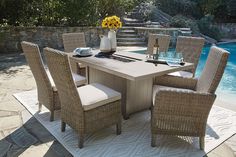 an outdoor dining table and chairs near a pool