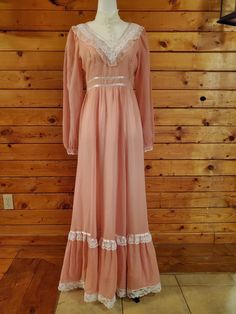 This darling pink Victorian vintage Gunne Sax prairie dress from the 1970s, features a pastel pink fabric with lace detail on a high fitted neck, trimmed in satin ribbon and puff sleeves, and pearl button cuffs.  Includes tie at waist for adjusting to fit. The skirt is full and long with a satin ribbon and antique lace trimmed bottom ruffle and a full zipper back. This dress is authentic vintage and is in excellent condition. Best fits size small. Vintage sizes run smaller than modern sizes, so Pastel Pink Fabric, Vintage Halter Dress, Maxi Dress Vintage, Pink Victorian, Cute Floral Dresses, 70s Inspired Fashion, Black Floral Top, 1970s Dresses, Victorian Vintage