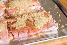 some meat is sitting on a metal pan with seasoning sprinkled around it