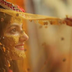 a woman with yellow powder on her face wearing a headdress and gold jewelry