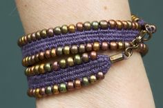 a woman's arm with three different bracelets on top of each other, one is purple and the other has gold beads