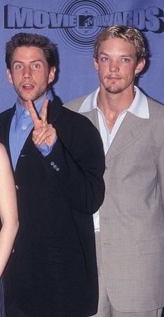 two men and a woman posing for the camera with their fingers up in front of them