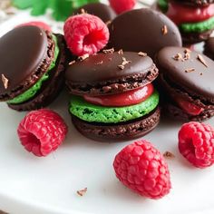 chocolate macaroons and raspberries on a white plate with green frosting