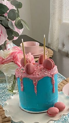 a blue cake with pink icing and sprinkles sitting on a table