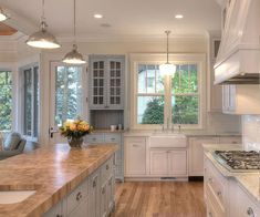 a large kitchen with white cabinets and wooden counter tops, along with an island in the middle