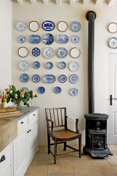 a room with plates on the wall and a chair in front of a stove top oven