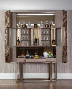 an entertainment center with wine bottles and glasses on it's shelves, in front of a wallpapered background