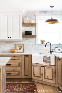 a kitchen with wooden cabinets and white counter tops, an area rug on the floor