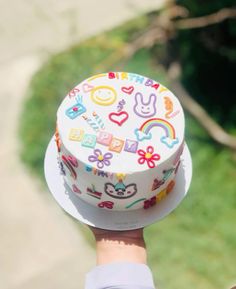 a person holding up a decorated birthday cake