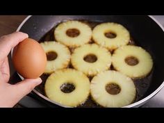 someone is holding an egg in a pan with pineapples