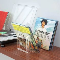 an old record player sitting on top of a wooden table next to a cd case