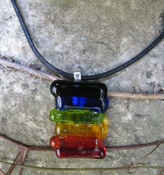 three different colored glass bottles sitting on top of a tree branch next to a stone wall