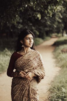 a woman in a sari walking down a dirt road