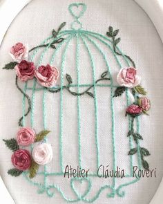 a birdcage with roses and leaves is shown on a white wall hanging hoop