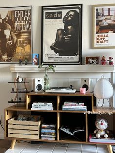 there is a book shelf with books on it and posters above the shelves in this room