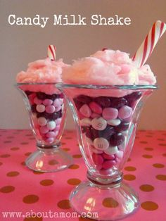 two cups filled with candy and marshmallows on top of a pink table