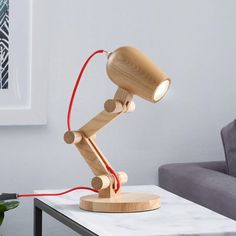 a wooden table lamp sitting on top of a white table next to a gray couch