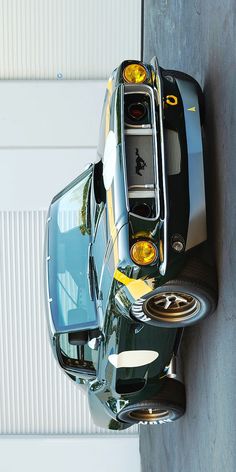 the top view of a black sports car parked in front of a garage door with it's lights on