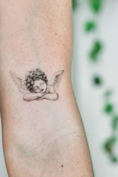 a small tattoo on the arm of a woman with an angel wings and headdress